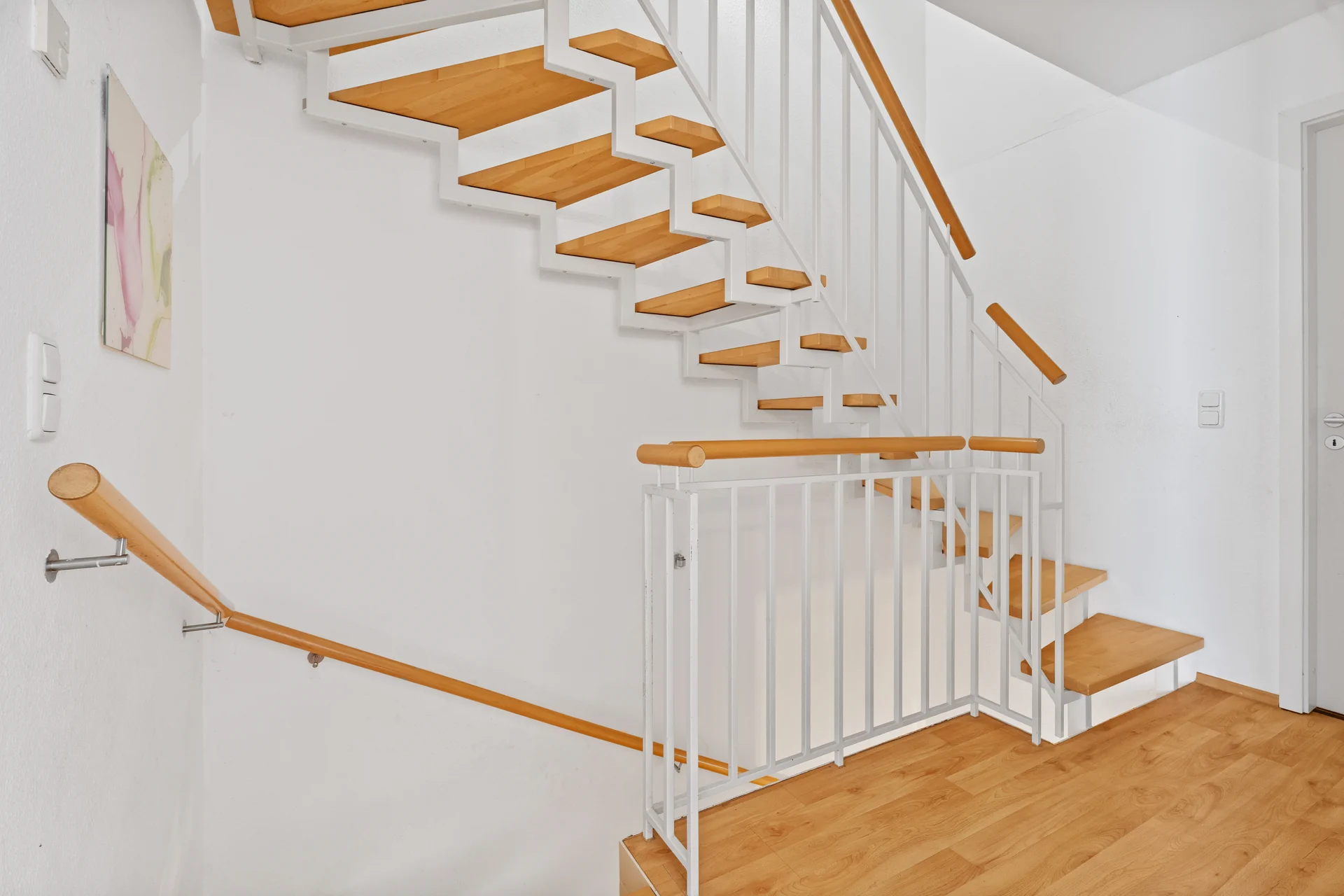 Heller Flurbereich mit moderner Treppe und Holzstufen