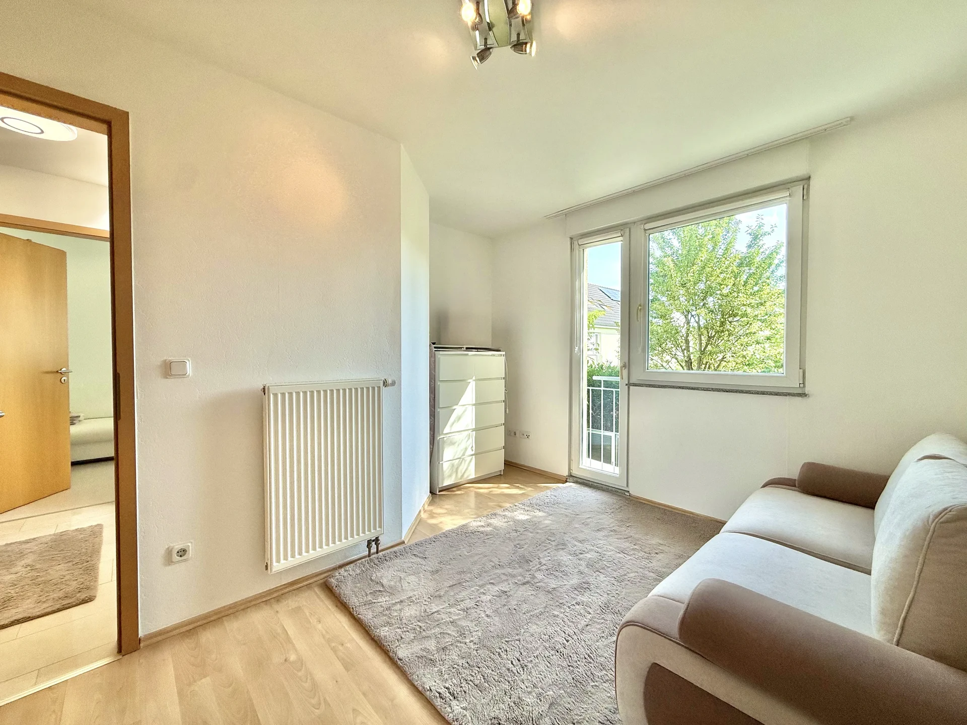 Freundliches Gästezimmer mit Fenster und Zugang zum Balkon