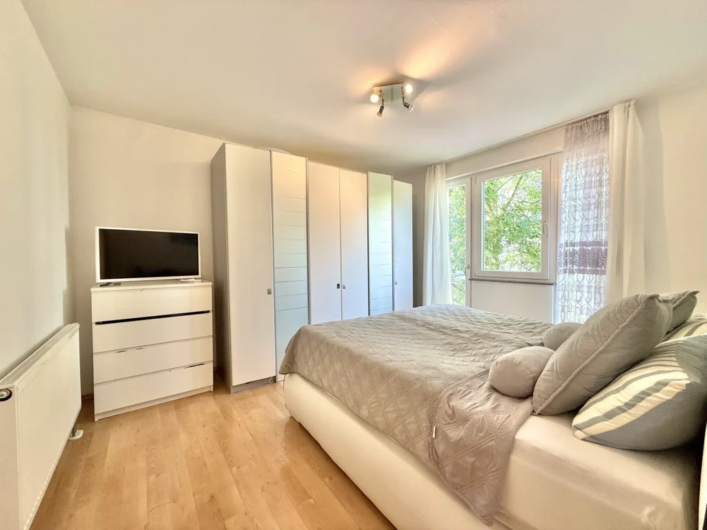 Helles Schlafzimmer mit großem Fenster und Einbauschrank