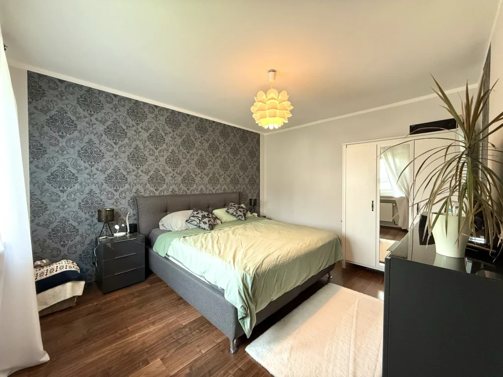 Schlafzimmer im ersten Obergeschoss mit Doppelbett und dekorativer Akzentwand