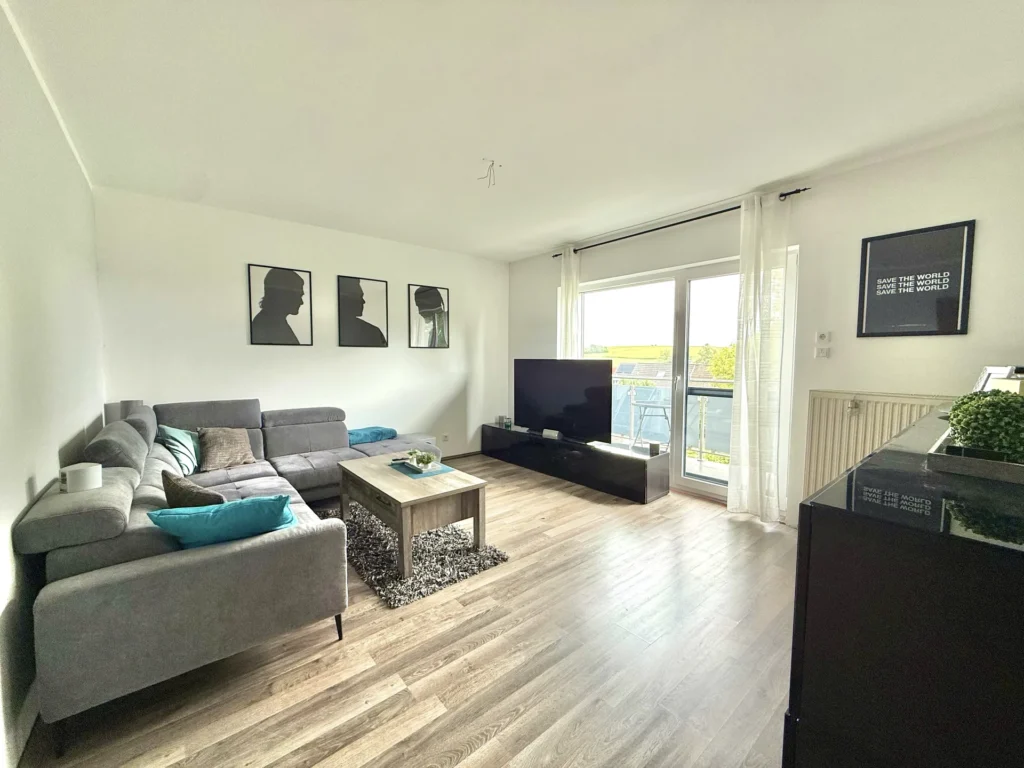 Helles Wohnzimmer im ersten Obergeschoss mit großer Fensterfront und Balkonzugang